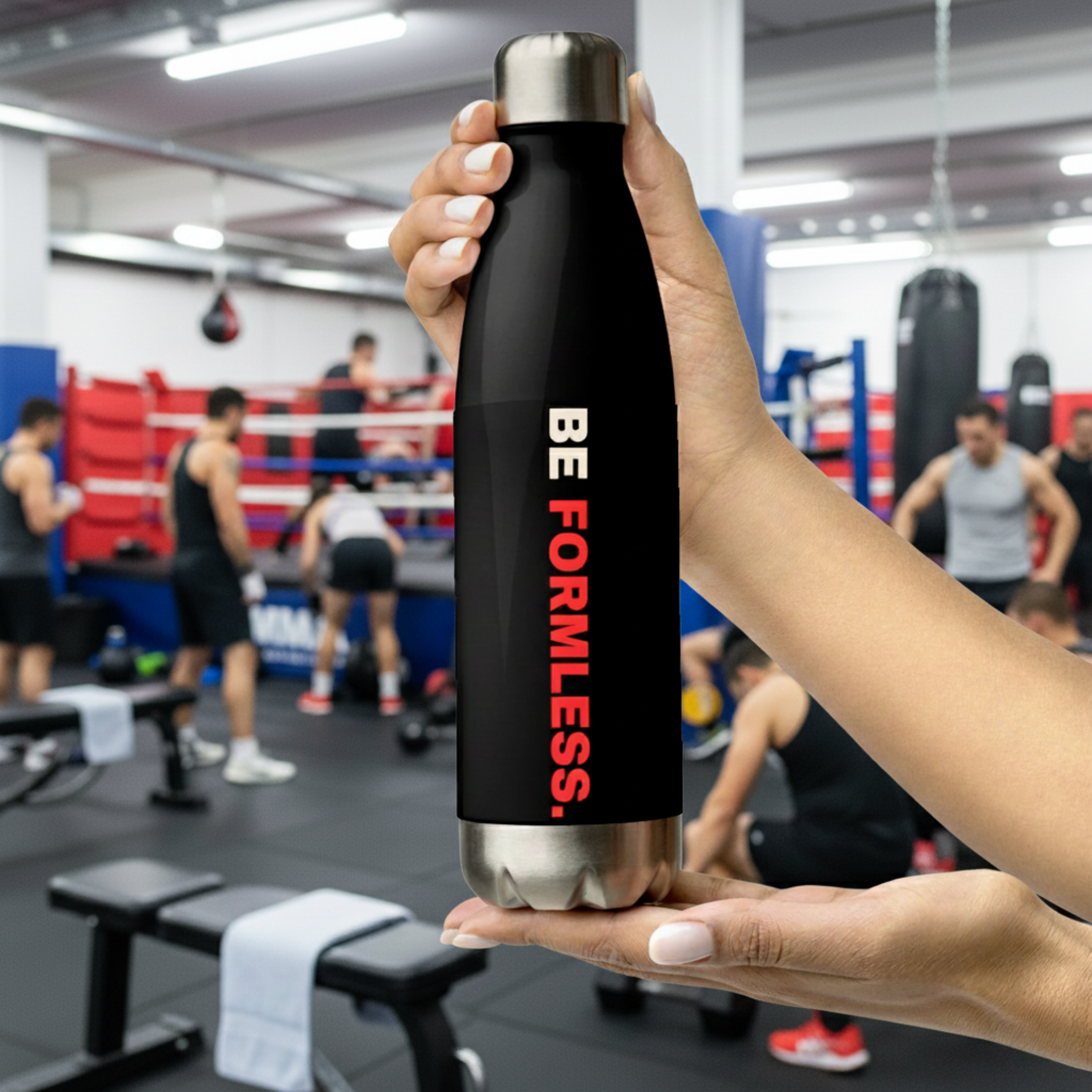 Person holding a black water bottle with 'BE FORMLESS' text in a gym setting