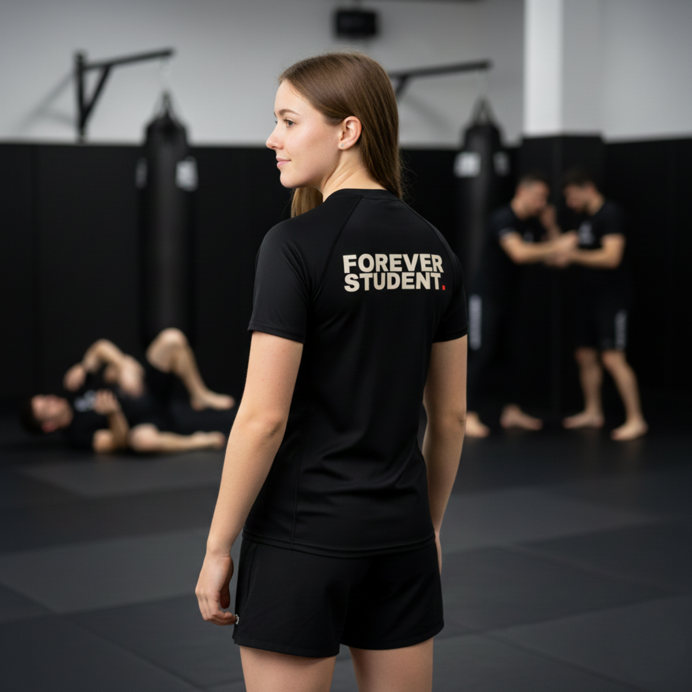 Person wearing a black t-shirt with 'Forever Student' text in a gym setting.