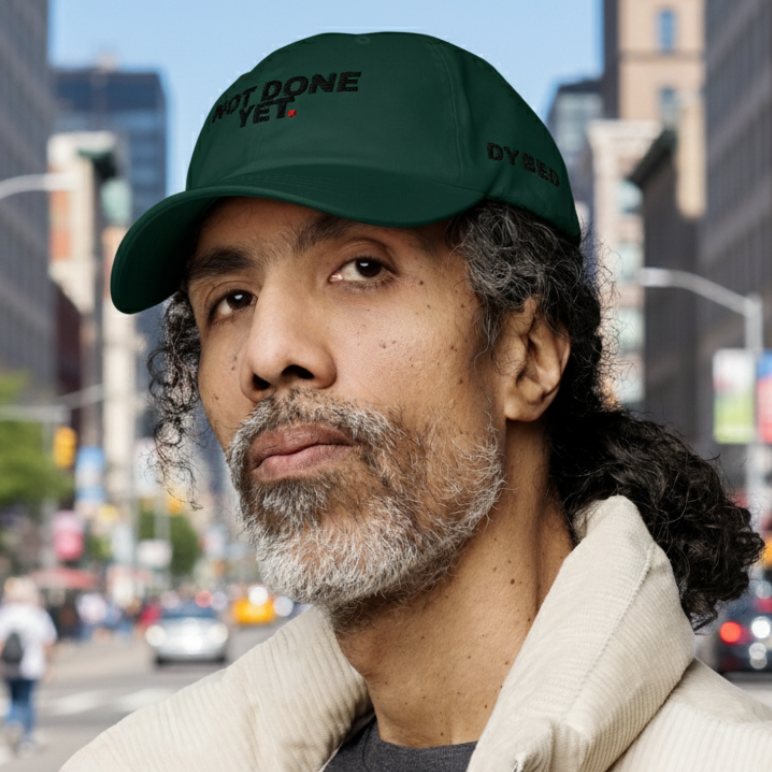 Man wearing a green cap with text in an urban setting