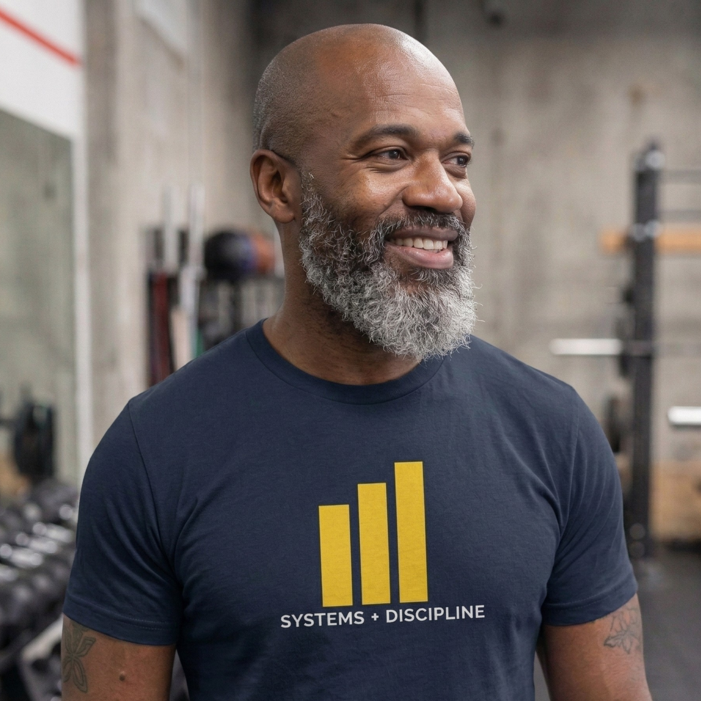 Man wearing a navy t-shirt with yellow graphics and text in a gym setting