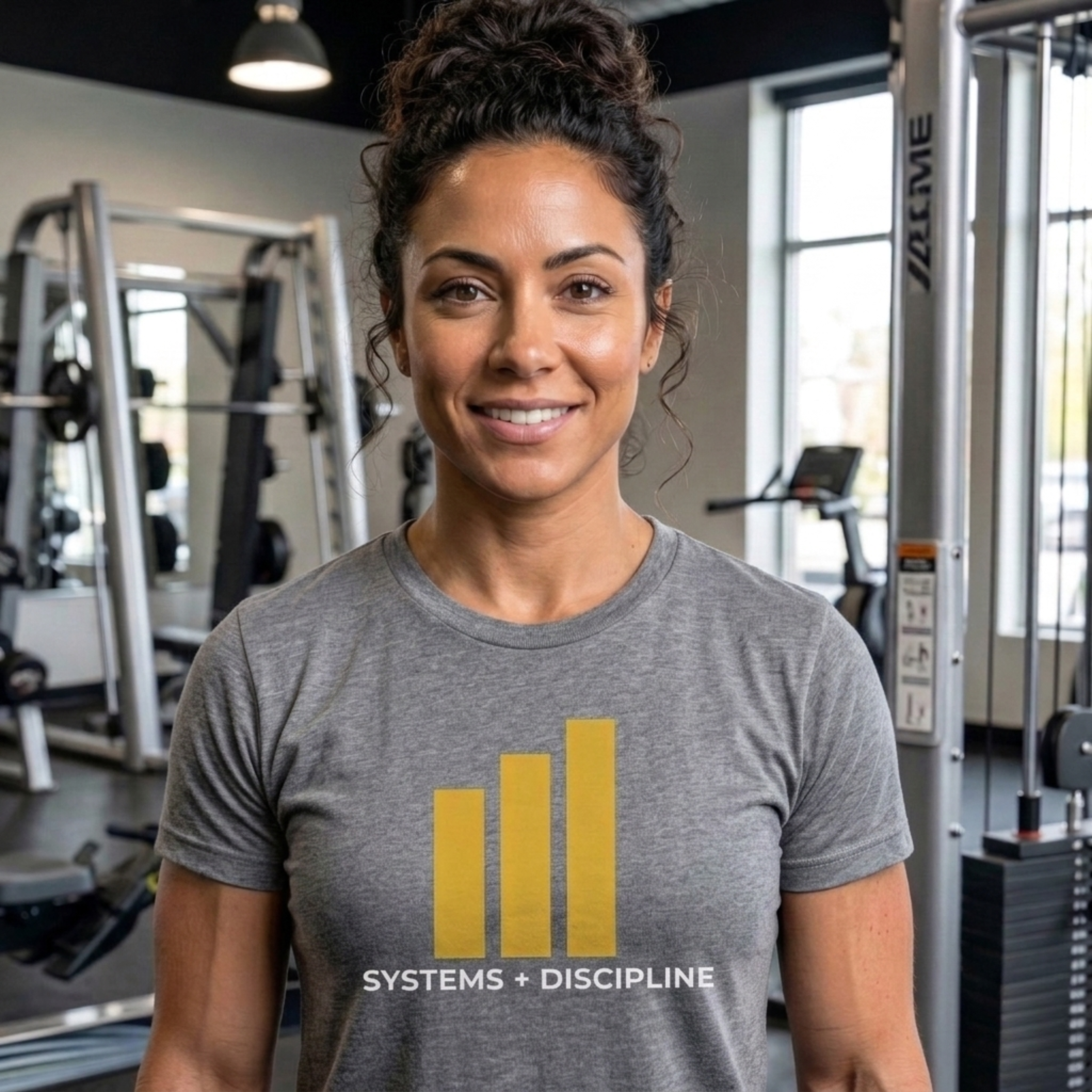 Woman wearing a gray t-shirt with a logo and text in a gym setting